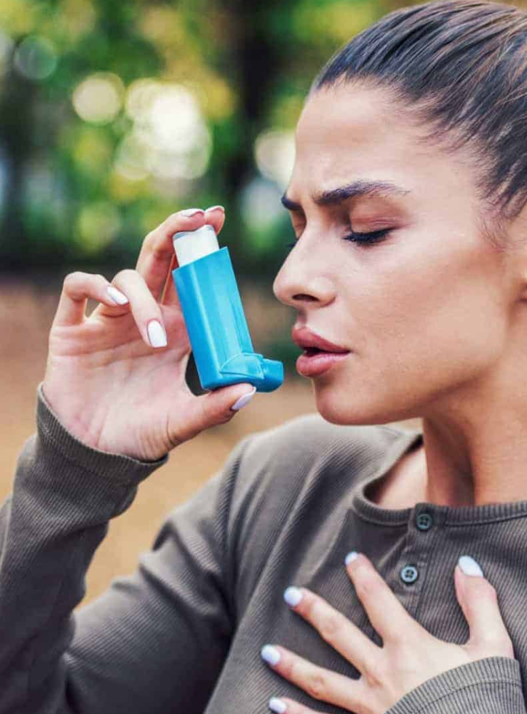 Mujer tomando medicamento con su inhalador.
