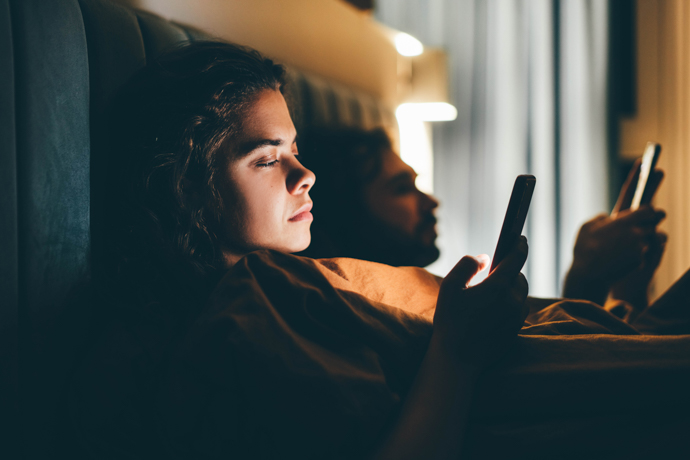 mujer mirando el celular en la cama de noche