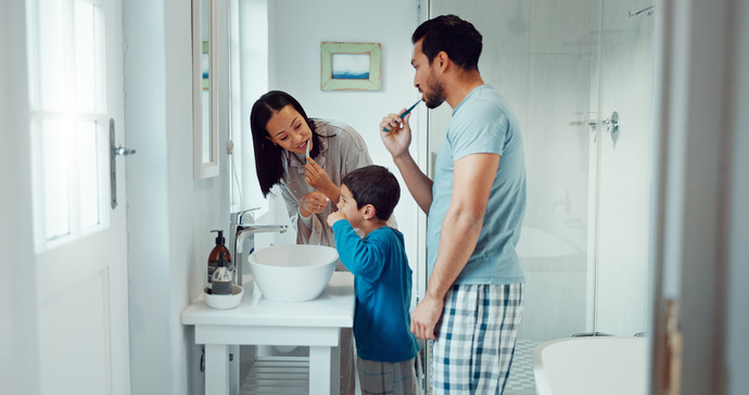 Familia con hijo pequeño lavándose los dientes en el baño