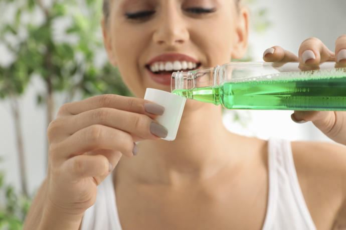 Mujer usa enjuague bucal para controlar inflamación de encías