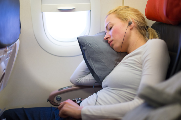 Mujer durmiendo en el avión, escuchando música
