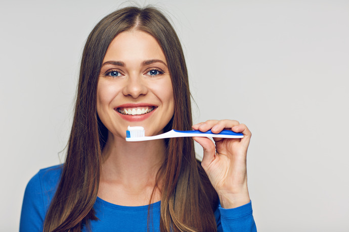 Mujer joven sonriente sujetando un cepillo de dientes