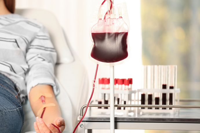 Mujer donando sangre con acercamiento a la bolsa de sangre