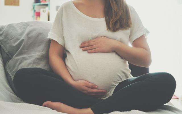 Embarazada sentada sujetándose la barriga