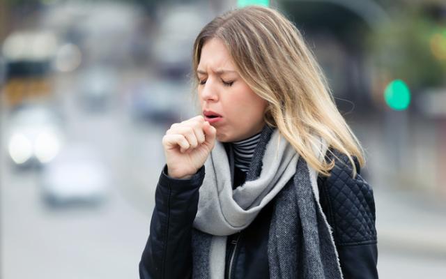 Mujer joven tosiendo en la calle