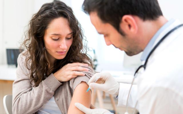 Médico poniendo una vacuna a una mujer joven