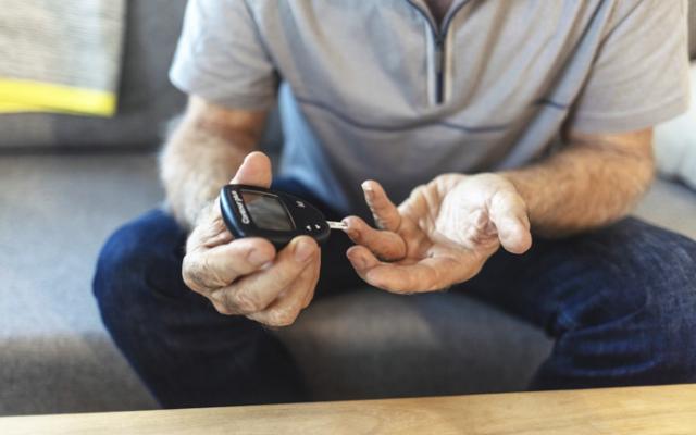 Hombre revisa glucosa en sangre con glucómetro