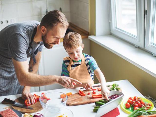 Padre explicando a hijo como cortar un tomate.