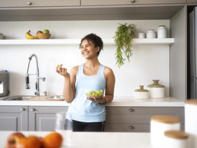 Mujer en Colombia preparando una porción de frutas en su cocina para mantener un plan de déficit calórico saludable.