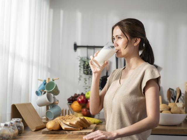 Mujer adulta disfrutando un vaso de leche, fuente de calcio clave para prevenir la osteoporosis.