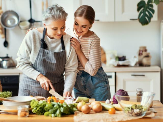 Mujer mayor con niña preparando comida saludable en la cocina