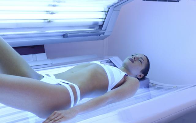Mujer con adicción al sol en cama de bronceado