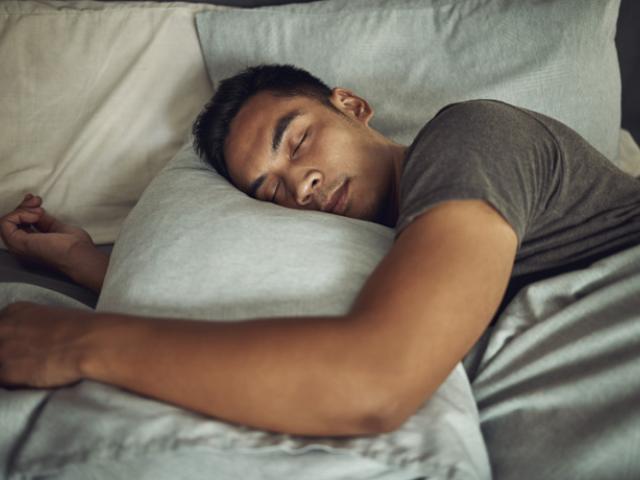 Un hombre en Colombia duerme profundamente en una habitación tranquila, siguiendo hábitos saludables de higiene del sueño para mejorar su bienestar.