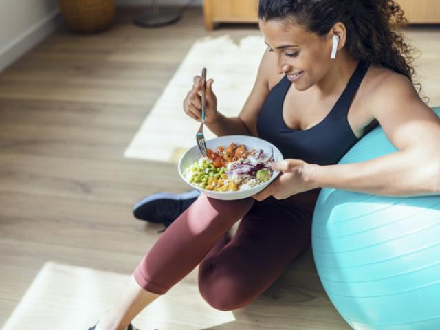 Mujer comiendo una ensalada después de hacer deporte, ejemplo de hábitos saludables. 